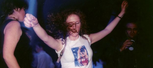Jeune fille aux cheveux bouclés portant un tee-shirt manga qui danse dans la greenroom aux Trans Musicales 1995 lors d'une soirée Planète