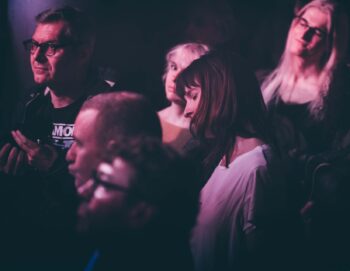 Photo de quelques personnes dans un public dont deux femmes écoutant la musique en fermant les yeux
