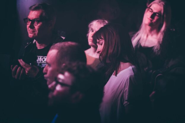 Photo de quelques personnes dans un public dont deux femmes écoutant la musique en fermant les yeux