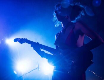 Photo en contre jour d'une femme jouant de la guitare électrique