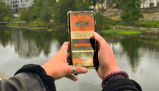 Gros plan sur des mains tenant un smartphone avec l'application du festival sur l'écran