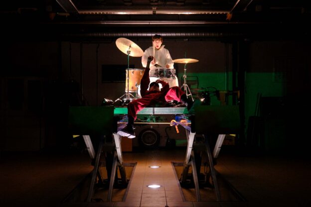 vue d'une petite scène sur laquelle un artiste chante allongé devant le batteur