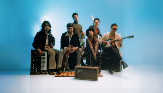 Photo studio d'un groupe d'artiste posant avec leurs instruments devant un fond neutre bleu